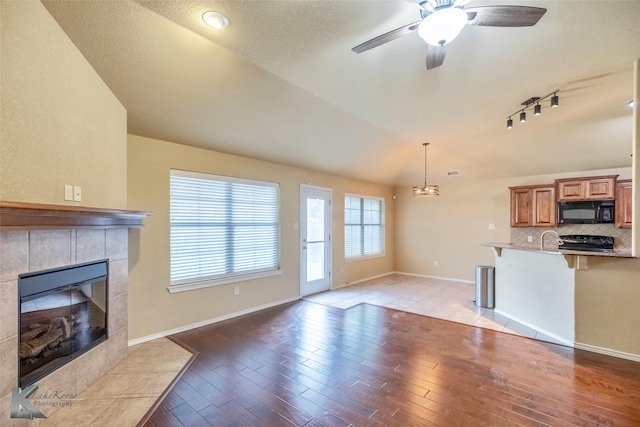 210 Miss Ellie Ln, Abilene, TX 79602 - unfurnished living room featuring light wood-type flooring, ceiling fan, a tiled fireplace, baseboards, and track lighting