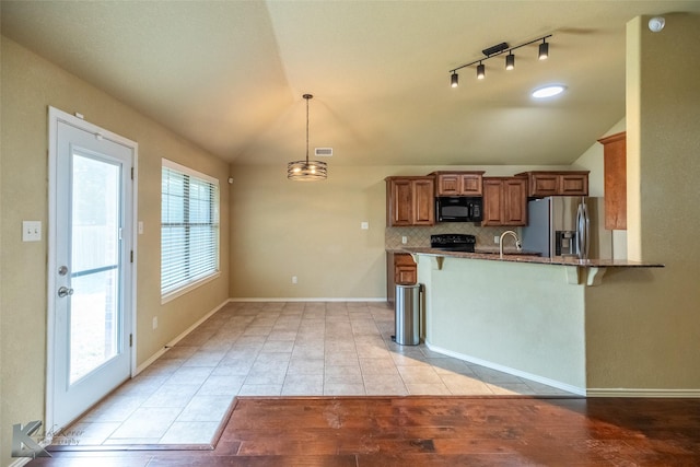210 Miss Ellie Ln, Abilene, TX 79602 - kitchen with black appliances, lofted ceiling, brown cabinets, a breakfast bar area, and tasteful backsplash