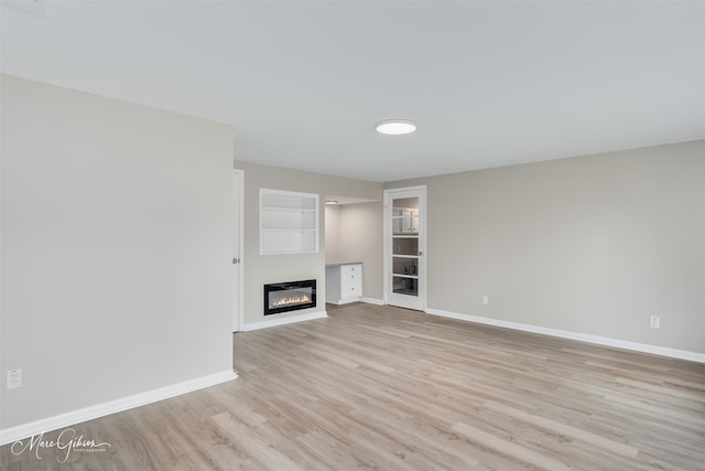 156 Charles Ave, Shreveport, LA 71105 - unfurnished living room with light wood-style flooring, a glass covered fireplace, and baseboards