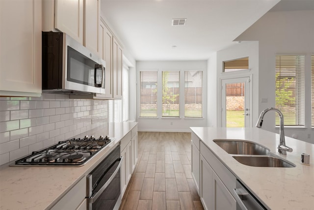 3104 Lakewood Bluffs Trl, Lewisville, TX 75010 - kitchen featuring stainless steel appliances, a sink, tasteful backsplash, baseboards, and light wood-type flooring