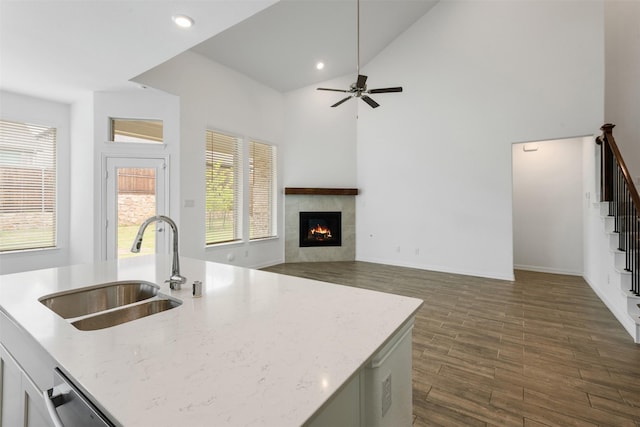 3104 Lakewood Bluffs Trl, Lewisville, TX 75010 - kitchen featuring a sink, dark wood-type flooring, a tiled fireplace, ceiling fan, and light stone countertops