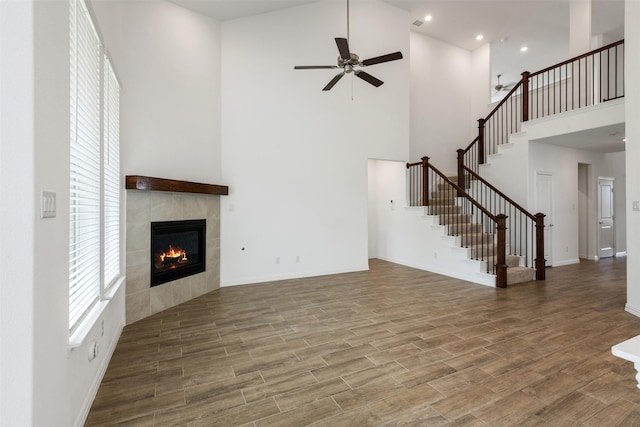 3104 Lakewood Bluffs Trl, Lewisville, TX 75010 - unfurnished living room with a high ceiling, ceiling fan, a fireplace, stairway, and wood finished floors