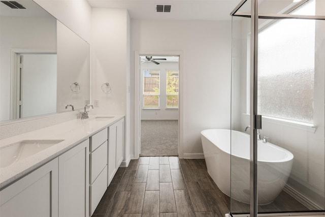 3104 Lakewood Bluffs Trl, Lewisville, TX 75010 - full bathroom featuring wood finished floors, a freestanding bath, double vanity, ceiling fan, and baseboards