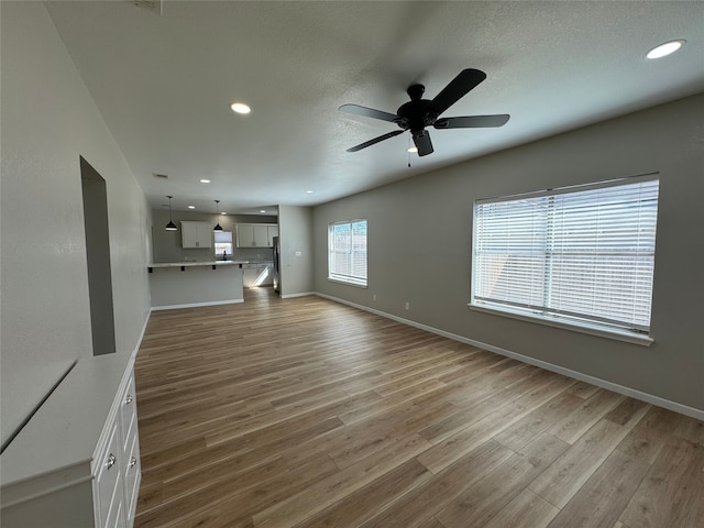608 S Seaman St, Eastland, TX 76448 - unfurnished living room featuring a ceiling fan, wood finished floors, recessed lighting, baseboards, and a textured ceiling