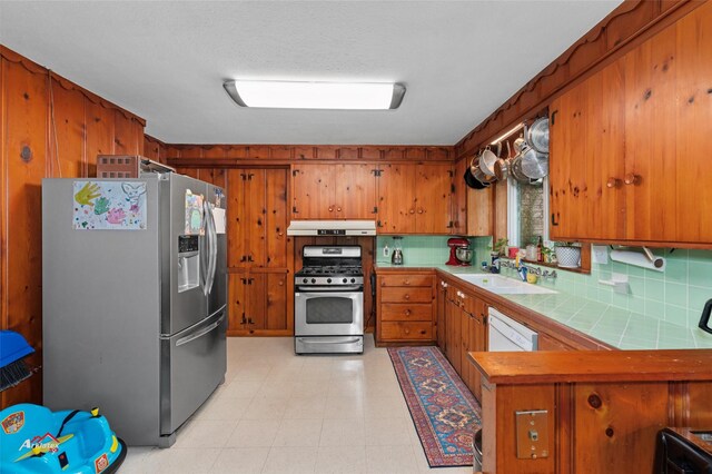 6237 Dillingham Ave, Shreveport, LA 71106 - kitchen with stainless steel appliances, under cabinet range hood, brown cabinets, tile counters, and decorative backsplash