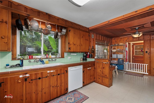 6237 Dillingham Ave, Shreveport, LA 71106 - kitchen featuring dishwasher, tile countertops, a sink, brown cabinetry, and wood walls