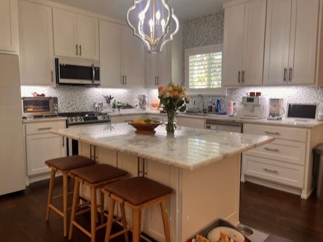 406 Barnes St, Mckinney, TX 75069 - kitchen with stainless steel appliances, white cabinetry, a center island, backsplash, and a breakfast bar area