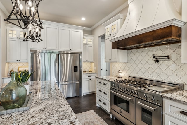 7404 Sandy Lake Rd, Quinlan, TX 75474 - kitchen with appliances with stainless steel finishes, a chandelier, ornamental molding, backsplash, and premium range hood