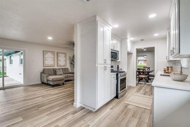 1106 Spring Lake Dr, Garland, TX 75043 - kitchen featuring appliances with stainless steel finishes, a sink, open floor plan, white cabinets, and recessed lighting