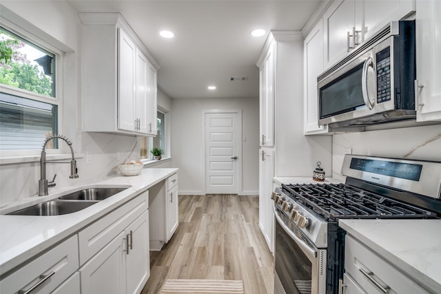 1106 Spring Lake Dr, Garland, TX 75043 - kitchen with appliances with stainless steel finishes, a sink, white cabinets, recessed lighting, and light wood-type flooring