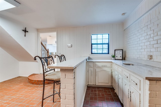 606 Quiram Ln, Kemp, TX 75143 - kitchen with brick floors, light countertops, a kitchen breakfast bar, a peninsula, and cream cabinets