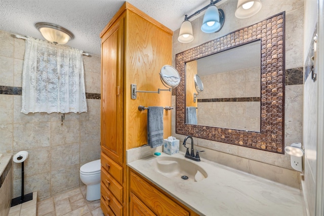 3245 Gail Ct, Irving, TX 75060 - bathroom featuring a textured ceiling, toilet, tile walls, and vanity
