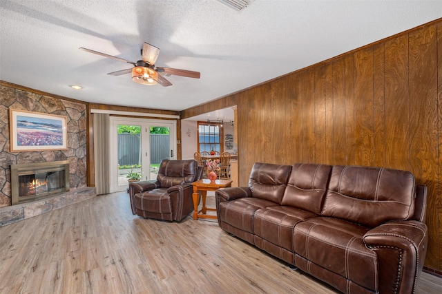 3245 Gail Ct, Irving, TX 75060 - living area featuring a ceiling fan, wooden walls, a textured ceiling, light wood-style floors, and a fireplace