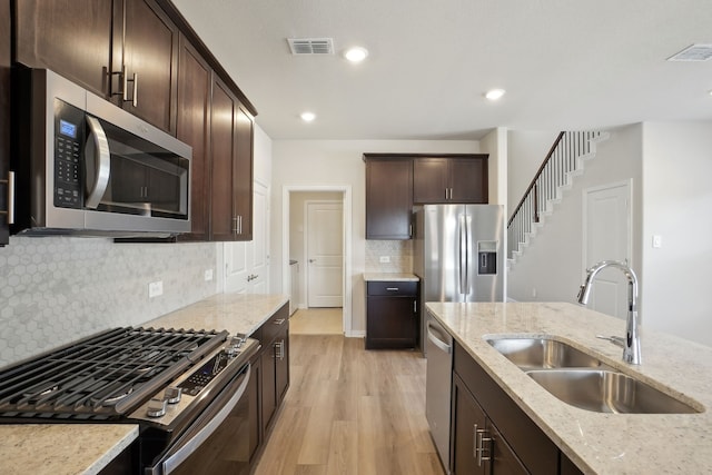 511 Willet Dr, Mckinney, TX 75069 - kitchen with stainless steel appliances, a sink, light wood finished floors, dark brown cabinetry, and light stone countertops