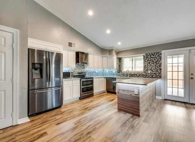510 Redbud Dr, Forney, TX 75126 - kitchen featuring stainless steel appliances, wall chimney range hood, white cabinets, tasteful backsplash, and crown molding