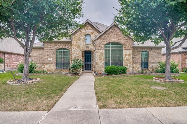 7611 Forest Ridge Trl, Sachse, TX 75048 - french country home featuring stone siding, a front yard, and roof with shingles