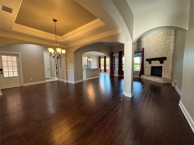 2802 Castlereach St, Trophy Club, TX 76262 - unfurnished living room with a chandelier, a tray ceiling, a stone fireplace, dark wood finished floors, and baseboards