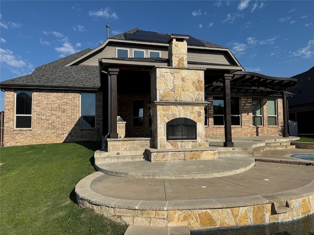 2802 Castlereach St, Trophy Club, TX 76262 - back of property with an outdoor stone fireplace, roof mounted solar panels, a patio, a lawn, and stone siding