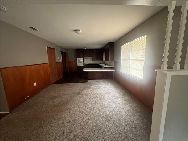101 Oakland Dr, Lacy Lakeview, TX 76705 - kitchen with white oven, light countertops, dark colored carpet, a peninsula, and wainscoting