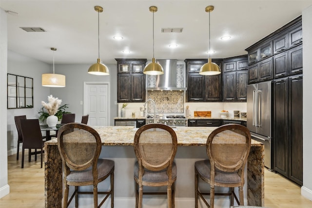 5213 Evening Sun Dr, Frisco, TX 75034 - kitchen featuring wall chimney exhaust hood, high quality fridge, tasteful backsplash, light wood-type flooring, and glass insert cabinets