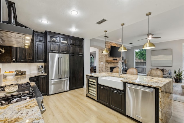 5213 Evening Sun Dr, Frisco, TX 75034 - kitchen featuring stainless steel appliances, beverage cooler, arched walkways, a sink, and light wood-type flooring