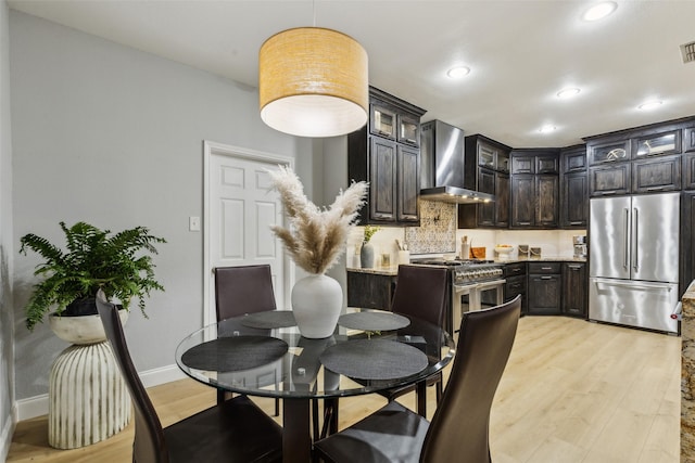 5213 Evening Sun Dr, Frisco, TX 75034 - kitchen featuring high quality appliances, wall chimney exhaust hood, light wood finished floors, glass insert cabinets, and recessed lighting