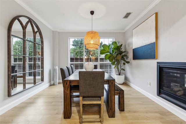 5213 Evening Sun Dr, Frisco, TX 75034 - dining space featuring light wood-style flooring, baseboards, ornamental molding, and a glass covered fireplace