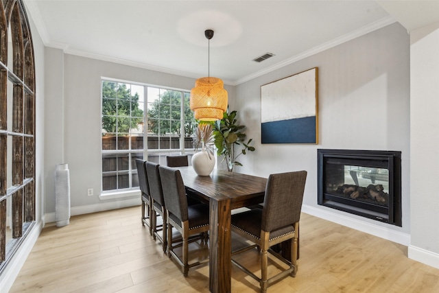 5213 Evening Sun Dr, Frisco, TX 75034 - dining area featuring light wood finished floors, crown molding, a multi sided fireplace, and baseboards