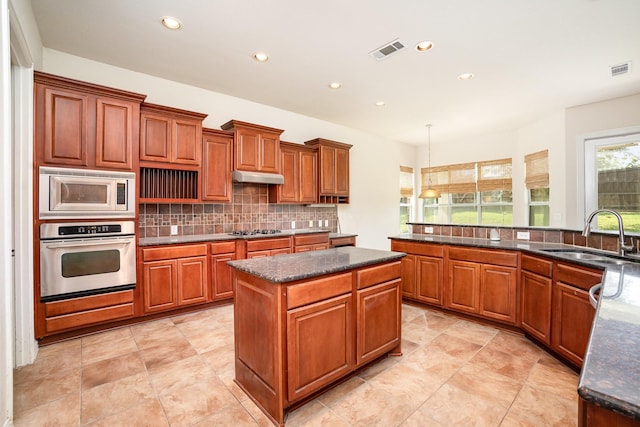 549 Verbena Ln, Frisco, TX 75036 - kitchen with appliances with stainless steel finishes, a sink, backsplash, a kitchen island, and under cabinet range hood