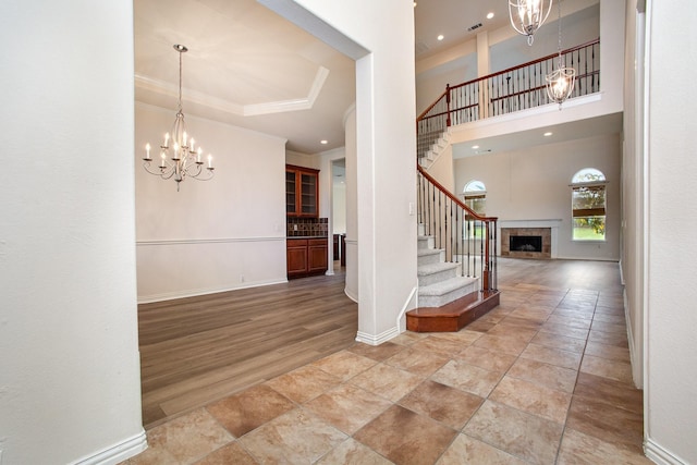 549 Verbena Ln, Frisco, TX 75036 - entrance foyer featuring a chandelier, crown molding, stairway, a tiled fireplace, and baseboards
