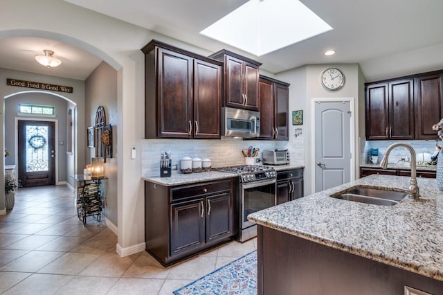 3103 Whispering Pine Blvd, Melissa, TX 75454 - kitchen featuring stainless steel appliances, a sink, light tile patterned floors, arched walkways, and recessed lighting