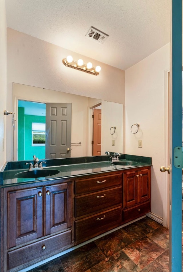 1100 County Road 12200, Paris, TX 75462 - bathroom featuring double vanity, stone finish floors, and a textured ceiling