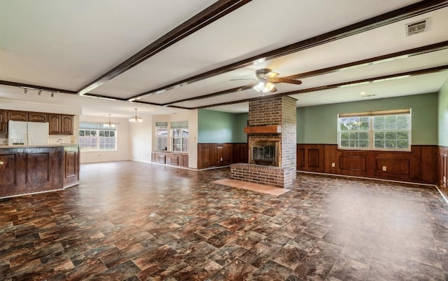 1100 County Road 12200, Paris, TX 75462 - unfurnished living room featuring a wainscoted wall, a brick fireplace, ceiling fan, healthy amount of natural light, and beamed ceiling