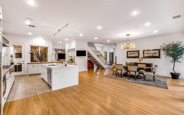 5624 Melshire Dr, Dallas, TX 75230 - kitchen with white cabinetry, a center island with sink, light countertops, light wood-style floors, and a sink