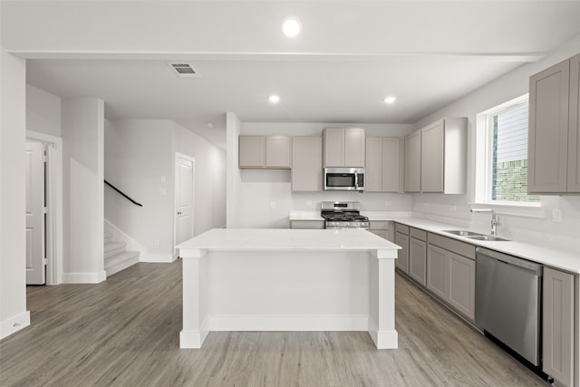 6728 Rockshire, Fort Worth, TX 76123 - kitchen with appliances with stainless steel finishes, gray cabinets, a center island, light wood finished floors, and light countertops