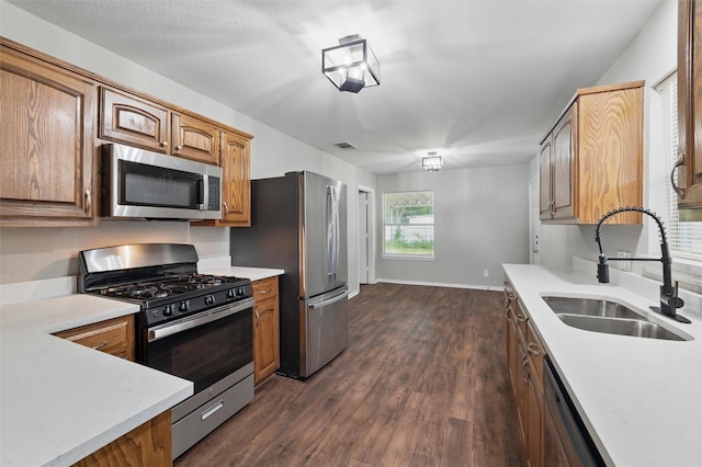 1625 Walnut St, Grand Prairie, TX 75050 - kitchen featuring stainless steel appliances, a sink, dark wood-style flooring, light countertops, and brown cabinets