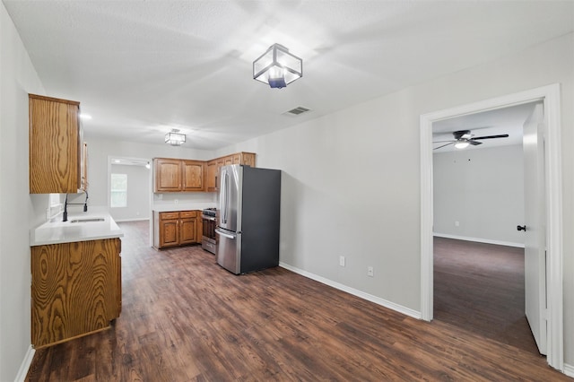 1625 Walnut St, Grand Prairie, TX 75050 - kitchen featuring stainless steel appliances, a sink, brown cabinetry, dark wood finished floors, and baseboards