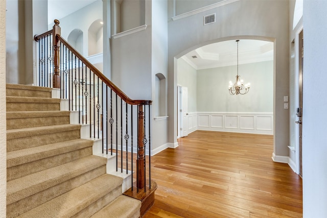225 Tipperary Dr, Keller, TX 76248 - foyer entrance featuring arched walkways, light wood-type flooring, ornamental molding, a decorative wall, and a chandelier