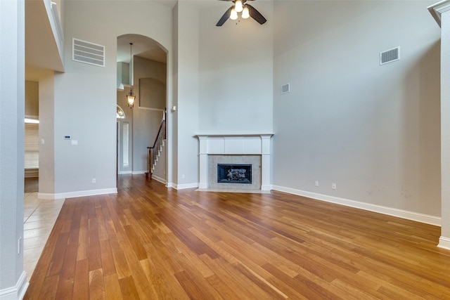 225 Tipperary Dr, Keller, TX 76248 - unfurnished living room with a towering ceiling, ceiling fan, arched walkways, light wood finished floors, and stairway