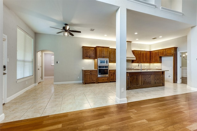 225 Tipperary Dr, Keller, TX 76248 - kitchen featuring stainless steel appliances, premium range hood, ceiling fan, arched walkways, and light countertops
