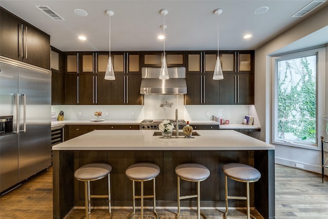4678 Christopher Pl, Dallas, TX 75204 - kitchen featuring stainless steel built in fridge, wall chimney exhaust hood, dark wood-style flooring, light countertops, and recessed lighting