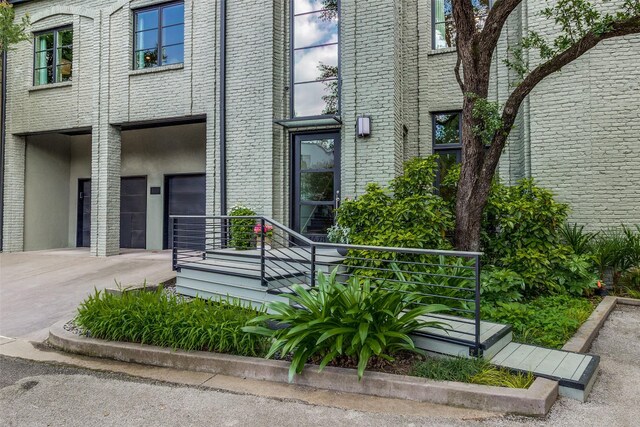4678 Christopher Pl, Dallas, TX 75204 - view of exterior entry with an attached garage, brick siding, and driveway