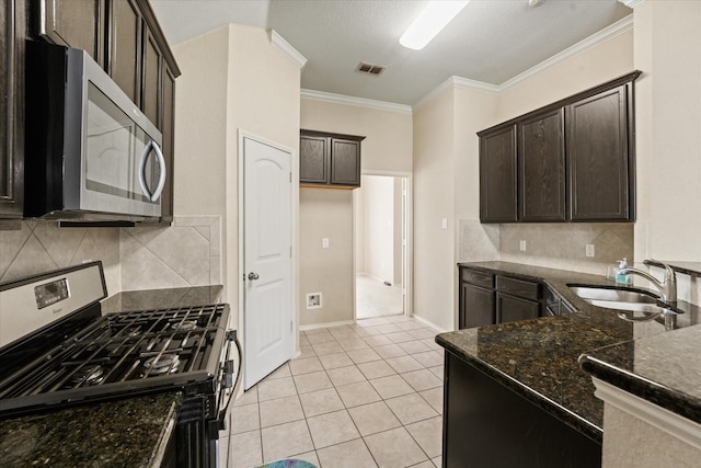 131 Wandering Dr, Forney, TX 75126 - kitchen with stainless steel appliances, a sink, dark stone countertops, crown molding, and dark brown cabinetry