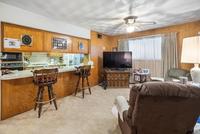 1728 Foster Dr, Arlington, TX 76012 - living room featuring a ceiling fan, light carpet, and wooden walls