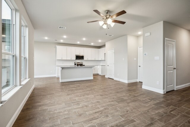 904 Santa Lucia Dr, Anna, TX 75409 - kitchen with appliances with stainless steel finishes, a ceiling fan, open floor plan, a center island with sink, and dark wood-style floors