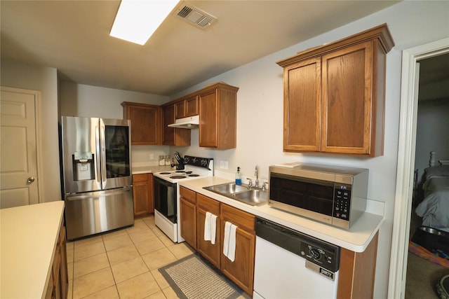 4009 Shiraz Dr, Denton, TX 76226 - kitchen featuring stainless steel appliances, under cabinet range hood, light countertops, light tile patterned floors, and a sink