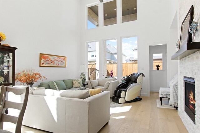 16098 Garganey Ct, Frisco, TX 75035 - living room with a towering ceiling, a warm lit fireplace, and light wood-style flooring
