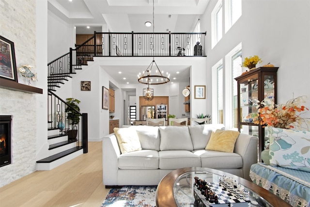 16098 Garganey Ct, Frisco, TX 75035 - living room with a high ceiling, light wood-style floors, stairs, a chandelier, and a stone fireplace