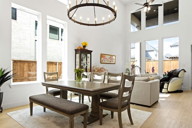 16098 Garganey Ct, Frisco, TX 75035 - dining space with light wood-type flooring, a towering ceiling, a chandelier, a ceiling fan, and baseboards
