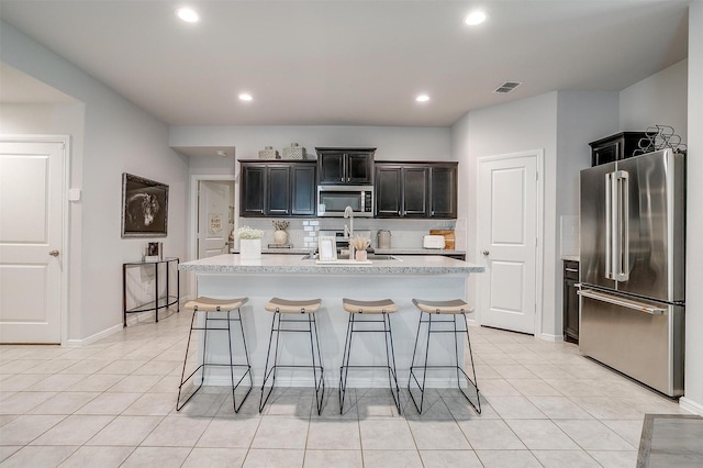 16556 White Fish Ln, Justin, TX 76247 - kitchen featuring stainless steel appliances, light countertops, decorative backsplash, a kitchen bar, and a kitchen island with sink